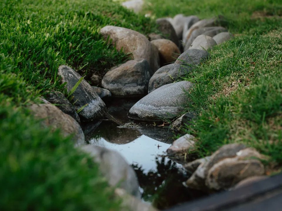 Stone-lined drainage channel through a lawn